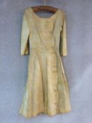 An antique floral embroidered yellow silk dress on Claridges hanger. With buttons up the side.