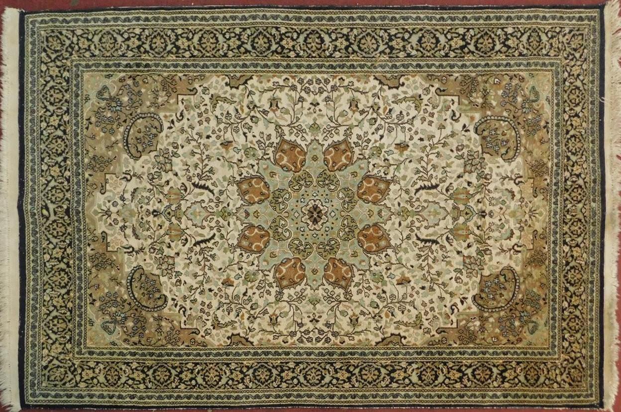 A silk Kashan rug with double medallions of scrolling flower and vine decoration on biscuit field