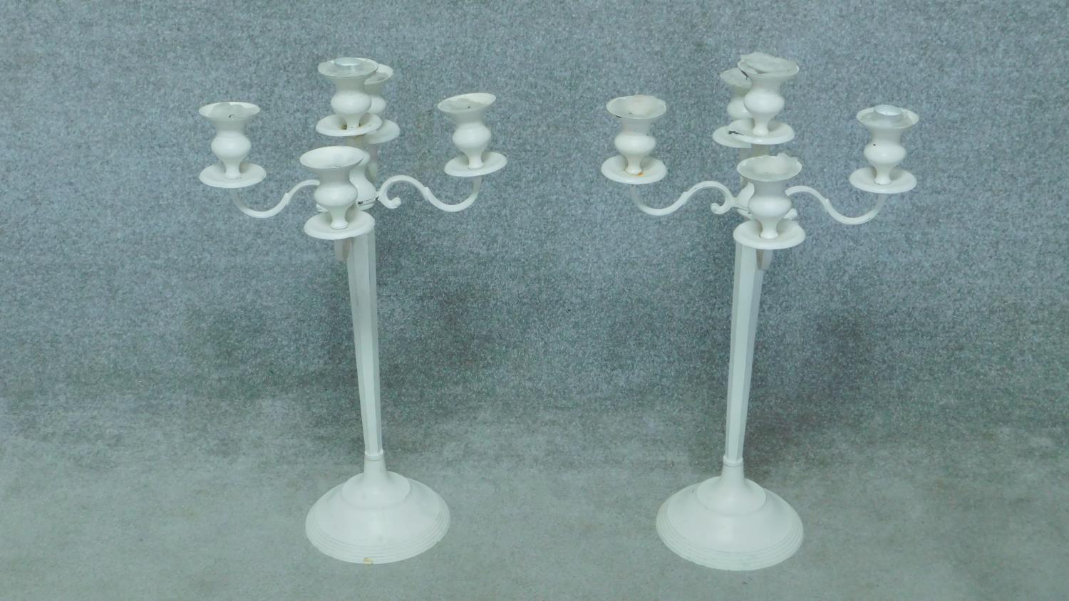 A pair of white painted metal five branch table candelabras. H.78cm