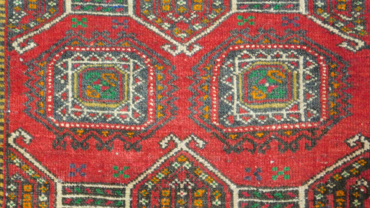 A Kazak rug with central lozenge medallions on a rouge field within floral multi borders and two - Image 2 of 4