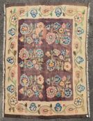 An antique Bessarabian Kilim rug with repeating highly stylised flowerhead design on a chocolate