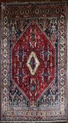 A Persian Kashkai rug with central lozenge medallion on madder ground contained within floral