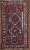 An antique Kazak rug with double lozenge medallion on indigo ground within a madder field