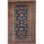 A Kazak rug with repeating stylised design across a midnight field within multiple borders. L.