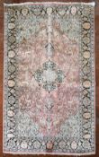 a Kashmir silk rug with floral medallion and spandrels on a salmon ground depicting animals in a