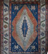 A Turkish Kazak rug with quadruple central medallions on an azure field within stylized triple