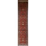 A Moughal style runner with repeating scrolling trellis central design within a border of serrated