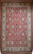 A Persian style flat weave carpet with scrolling leaves on madder ground within floral borders. L.