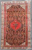 An antique Persian Malayer carpet with central hooked pole medallion on a stylised floral field