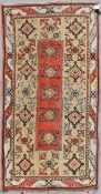 A Turkish Millas rug with repeating central flowerhead motif contained within broad stylised borders