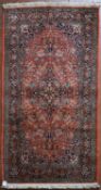 A silk Kashmir rug with central pendant medallion on madder field contained within floral