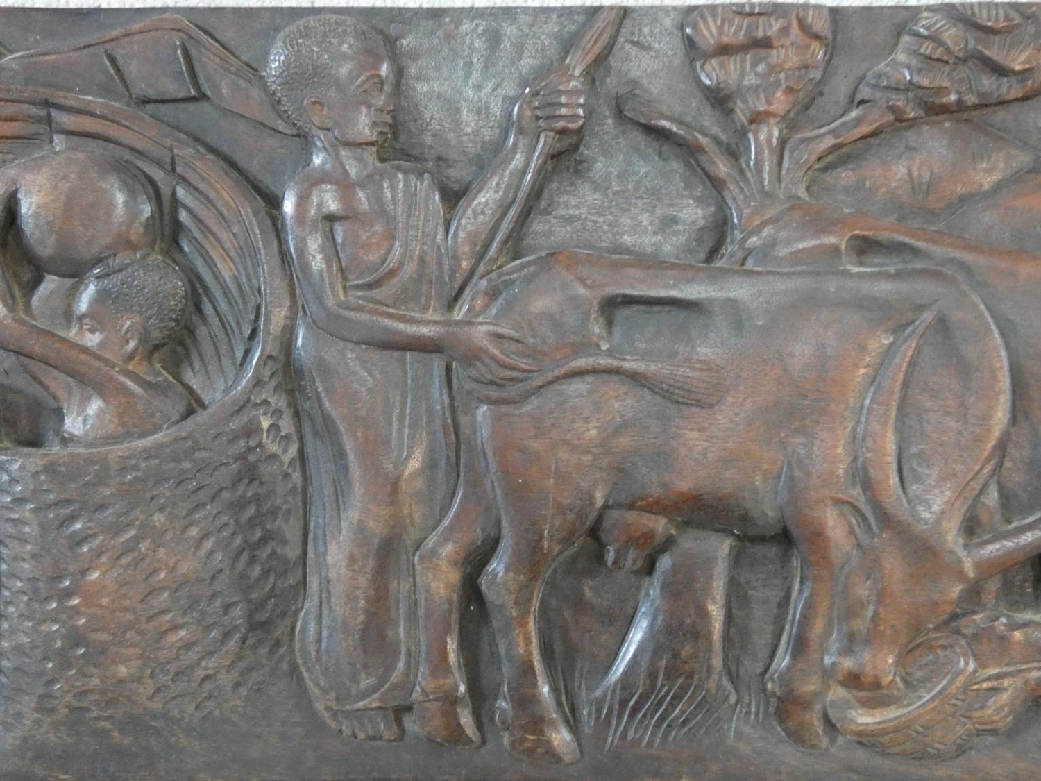 A carved African hardwood panel, farmers and cattle in a village setting, indistinctly signed to the - Image 3 of 7