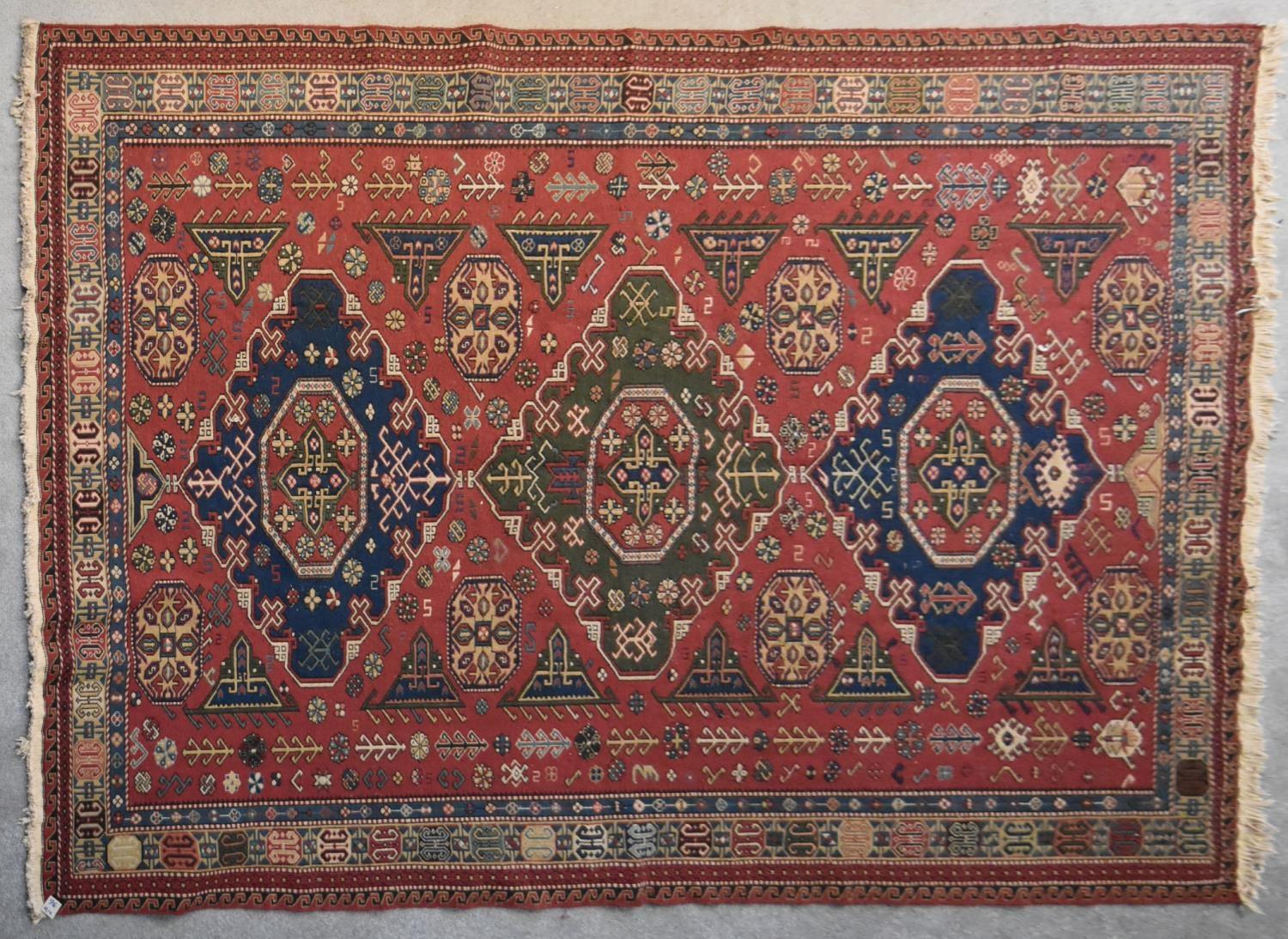 A Sumak Kilim with repeating pendant medallions on maroon ground surrounded by stylised floral and