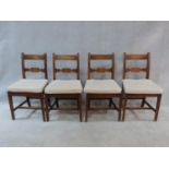 A set of four early 19th century mahogany dining chairs with carved backs and panel seats, fitted