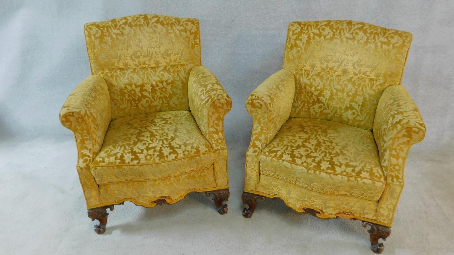 A pair of Georgian style armchairs in gold cut floral upholstery on walnut carved cabriole supports.
