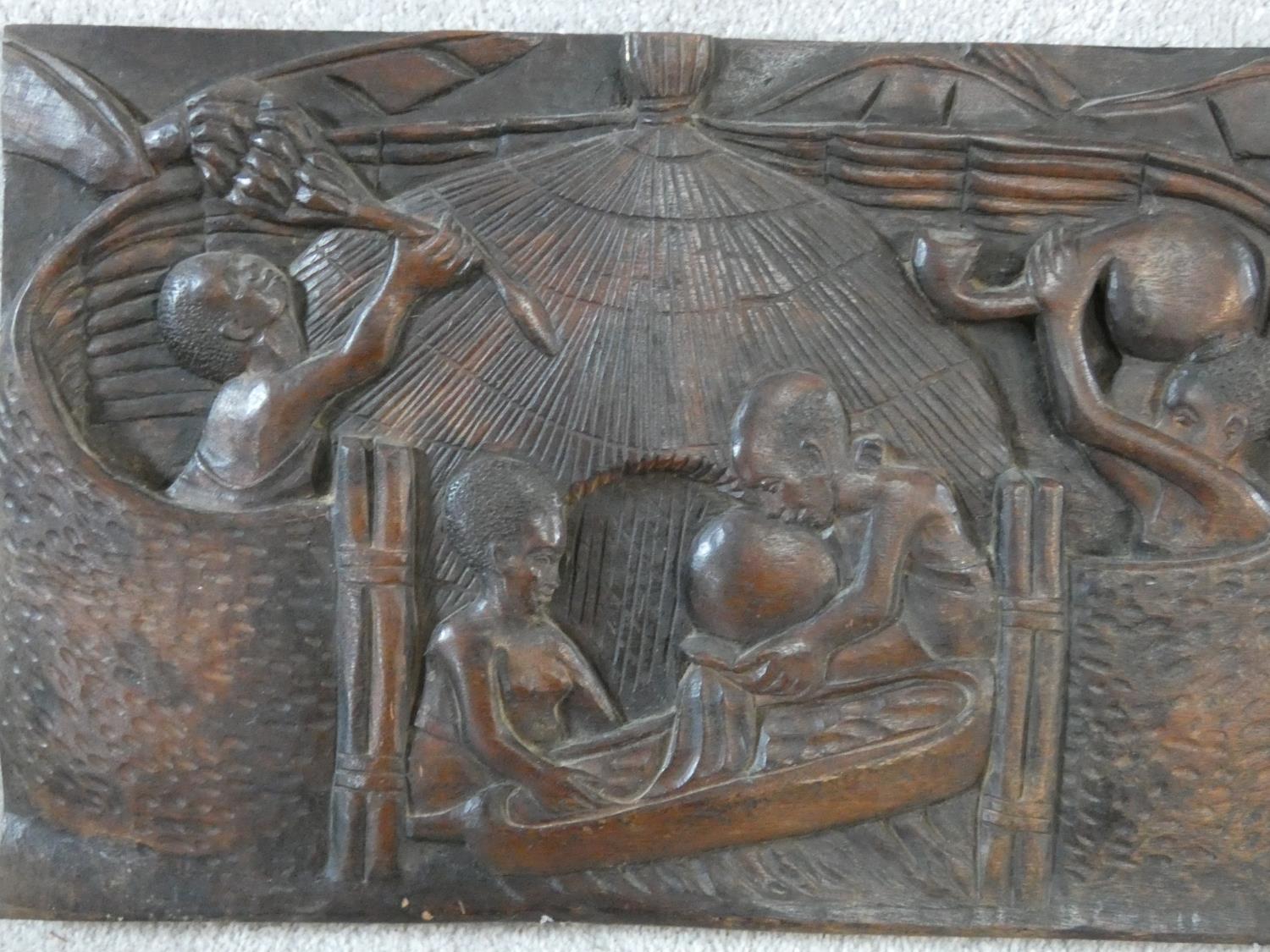 A carved African hardwood panel, farmers and cattle in a village setting, indistinctly signed to the - Image 2 of 7