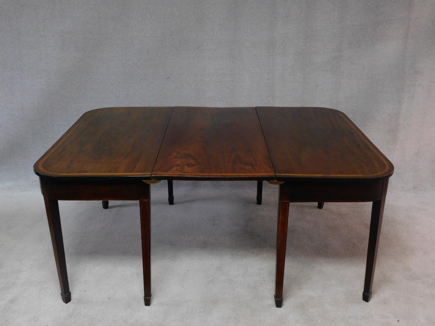 A late Georgian mahogany and satinwood strung D end dining table on square tapering supports and
