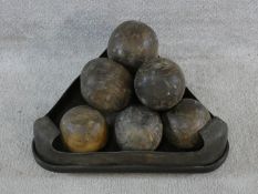 A set of replica wooden cannonballs in a triangular metal rimmed stand resting on three feet. L.46cm