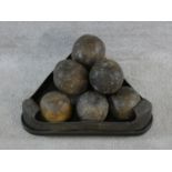 A set of replica wooden cannonballs in a triangular metal rimmed stand resting on three feet. L.46cm