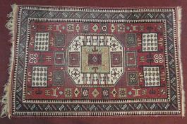 A Turkmenistan rug with central lozenge medallion on burgundy ground within geometric stylised