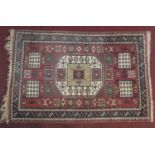 A Turkmenistan rug with central lozenge medallion on burgundy ground within geometric stylised