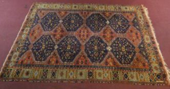 A Ushak carpet with repeating midnight lozenge medallions on a burgundy ground within geometric