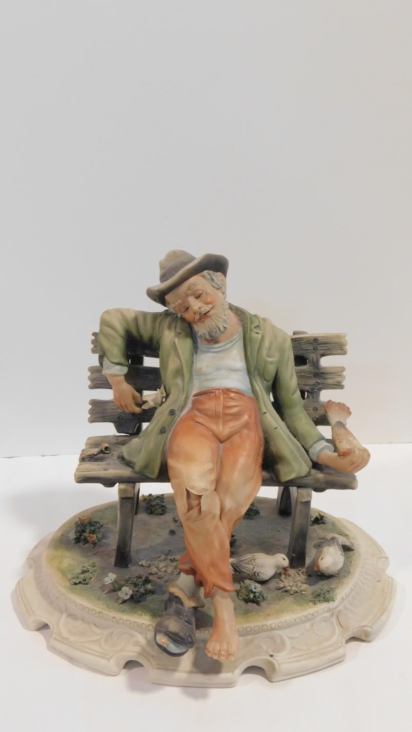 A Capodimonte figure of a man sitting on a bench, marked to the base. H.25cm