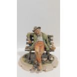 A Capodimonte figure of a man sitting on a bench, marked to the base. H.25cm