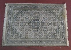 An Indian woollen rug with allover repeating floral motifs on ivory field within naturalistic