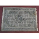 An Indian woollen rug with allover repeating floral motifs on ivory field within naturalistic