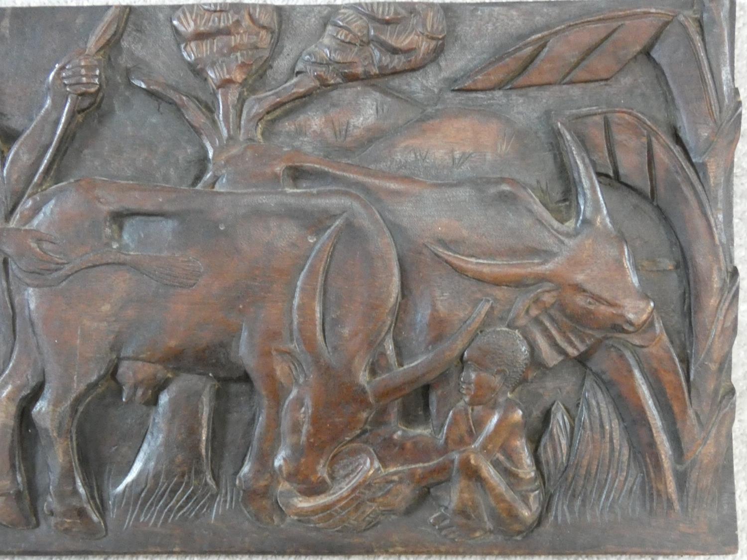 A carved African hardwood panel, farmers and cattle in a village setting, indistinctly signed to the - Image 4 of 7