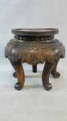 An antique Chinese hardwood urn stand with all-over floral carving on five scrolling cabriole