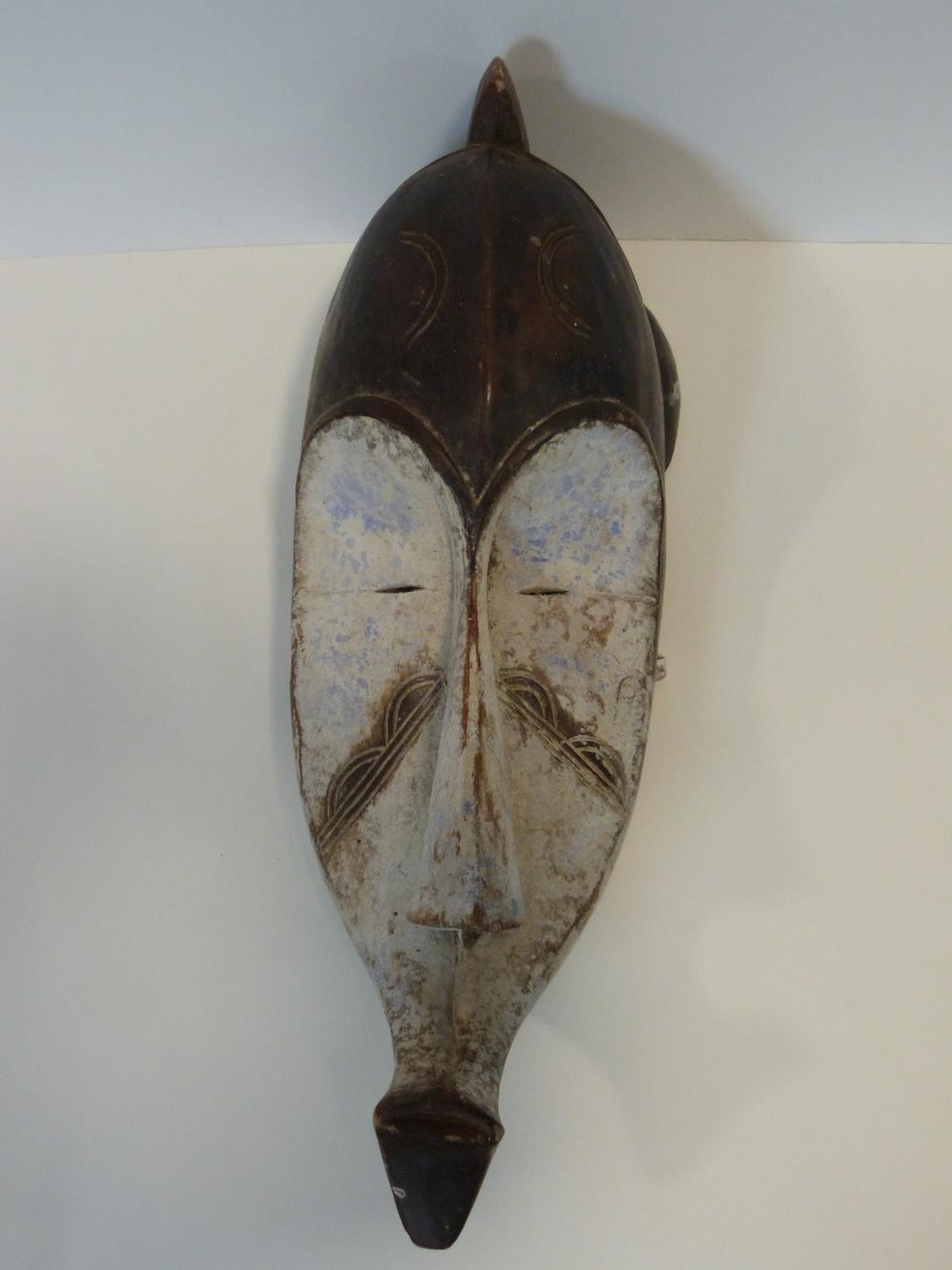 A carved and painted African DRC Gabon Fang Ngil wooden mask. H.56cm