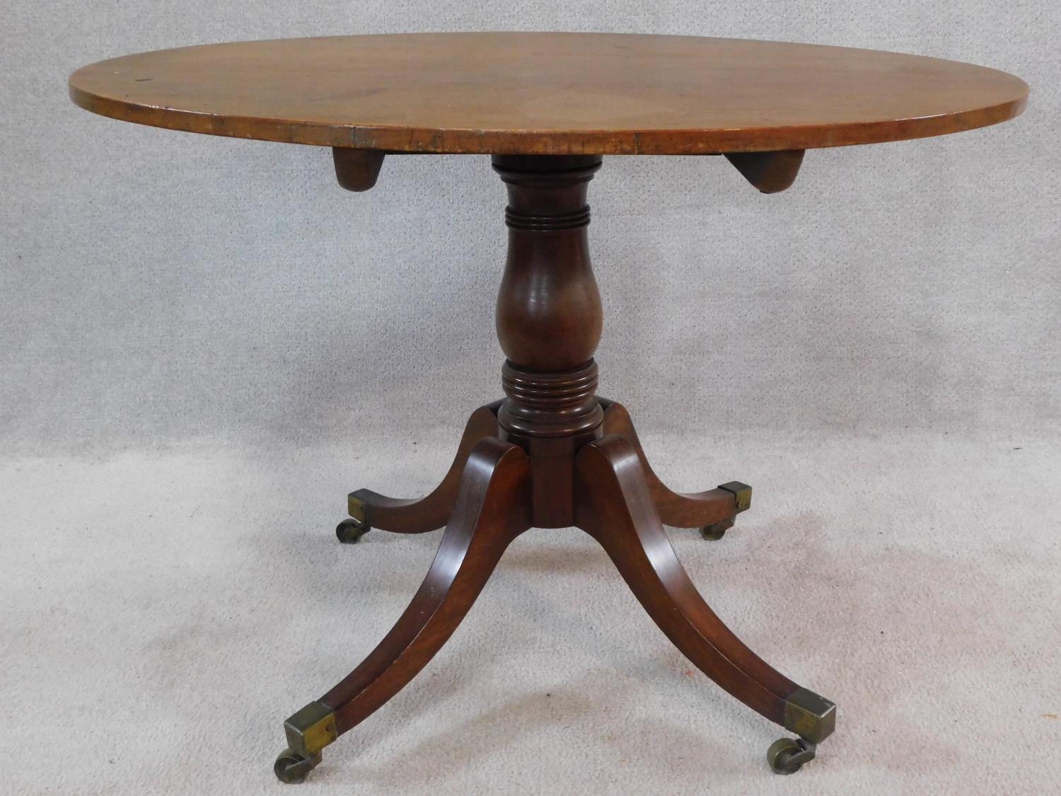 A 19th century mahogany tilt top tea table on swept quadruped supports terminating in brass cap