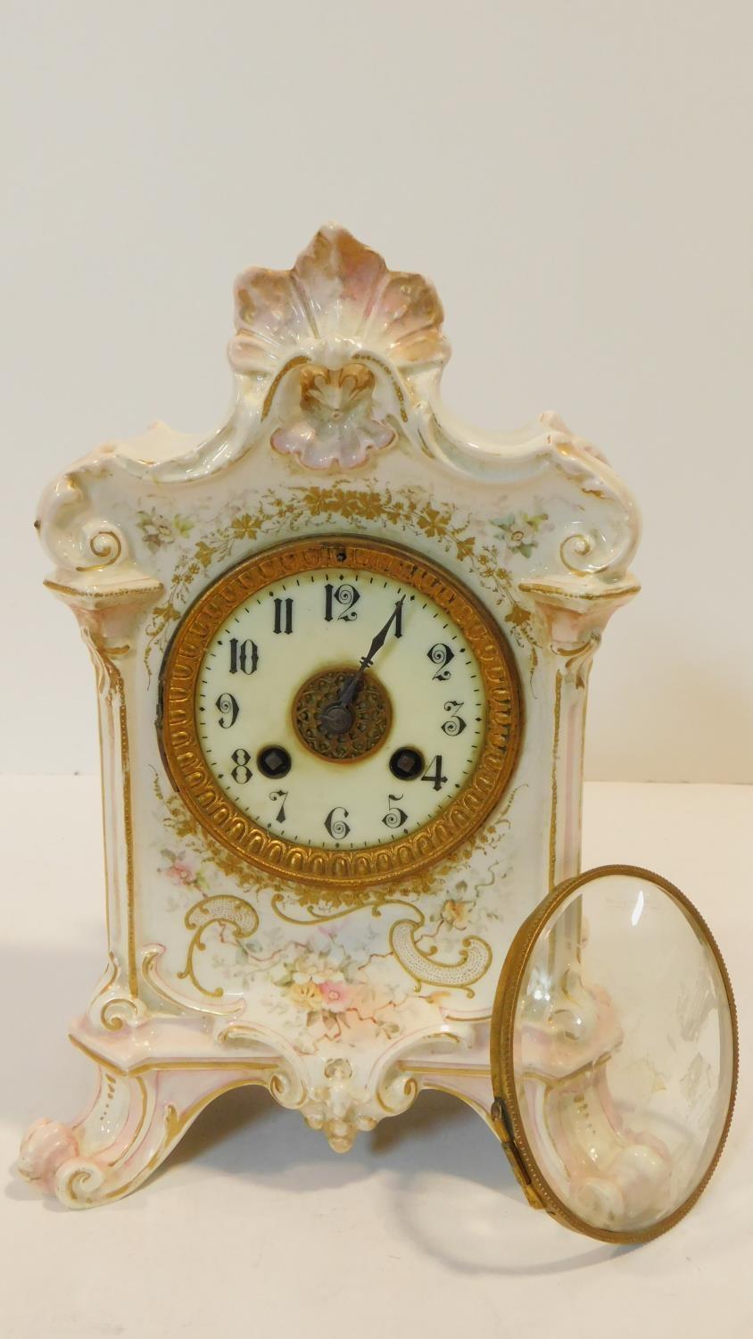 A porcelain hand painted antique gilded mantel clock with floral details and white enamel dial