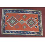 A Qashqai kelim rug with repeating diamond medallions on a terracotta field within geometric