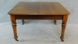 A 19th century mahogany extending dining table on turned tapering supports with extra leaf and