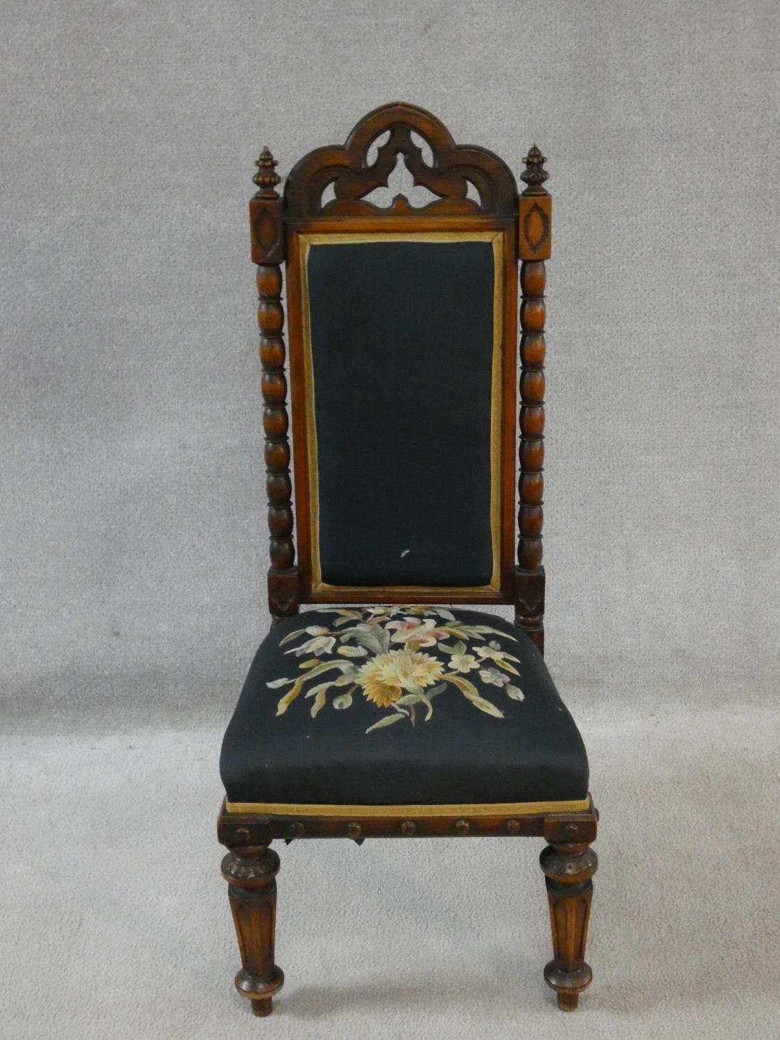 A late Victorian walnut Gothic carved prie dieu style side chair in floral tapestry upholstery. H.