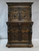An antique oak court cupboard of compact size with carved arched panel doors with central lozenge