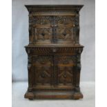 An antique oak court cupboard of compact size with carved arched panel doors with central lozenge