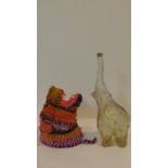 A multicoloured wall mounted lions head made from striped rope along with a glass bottle in the form