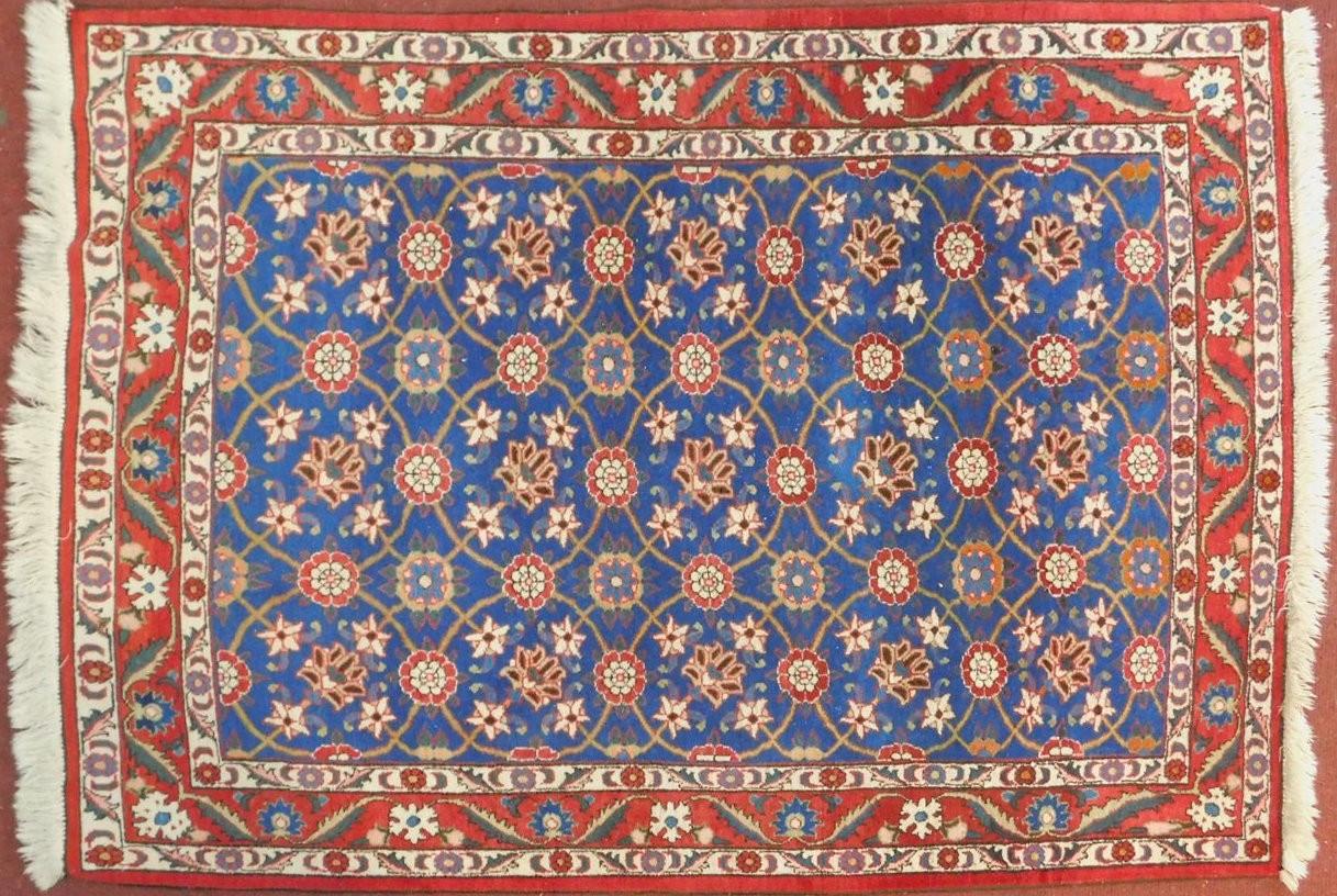 A Veramin Mina Khani style rug with repeating scrolling vine and floral decoration on a deep