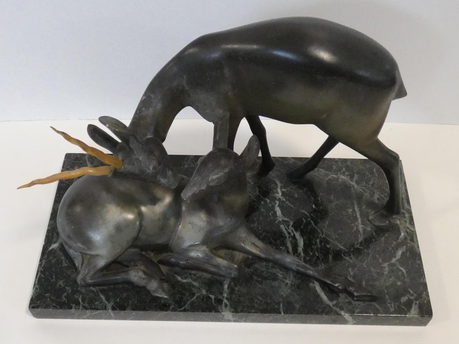 A pair of spelter Art Deco male and female gazelles mounted on a black and white veined marble base.