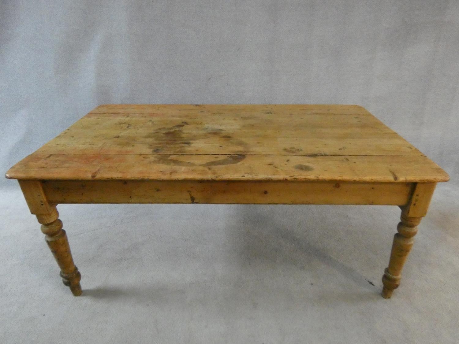 A Victorian pine kitchen dining table with planked top and end drawer on turned tapering supports.