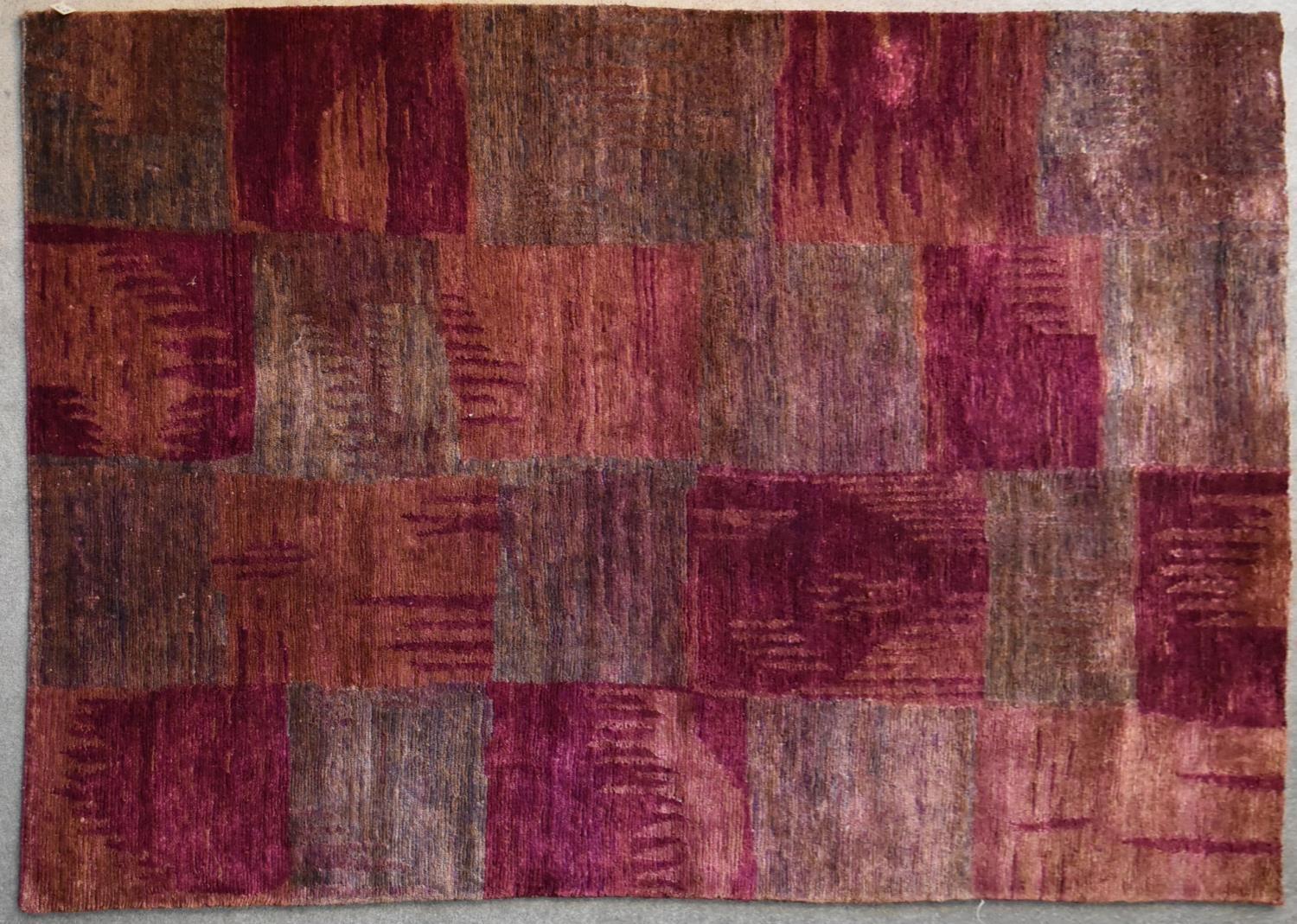 A contemporary rug with abstract chequerboard design in shades of plum. L.244x175cm