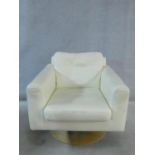 A vintage style revolving armchair in cream leather upholstery on circular laminated base. H.68 W.74