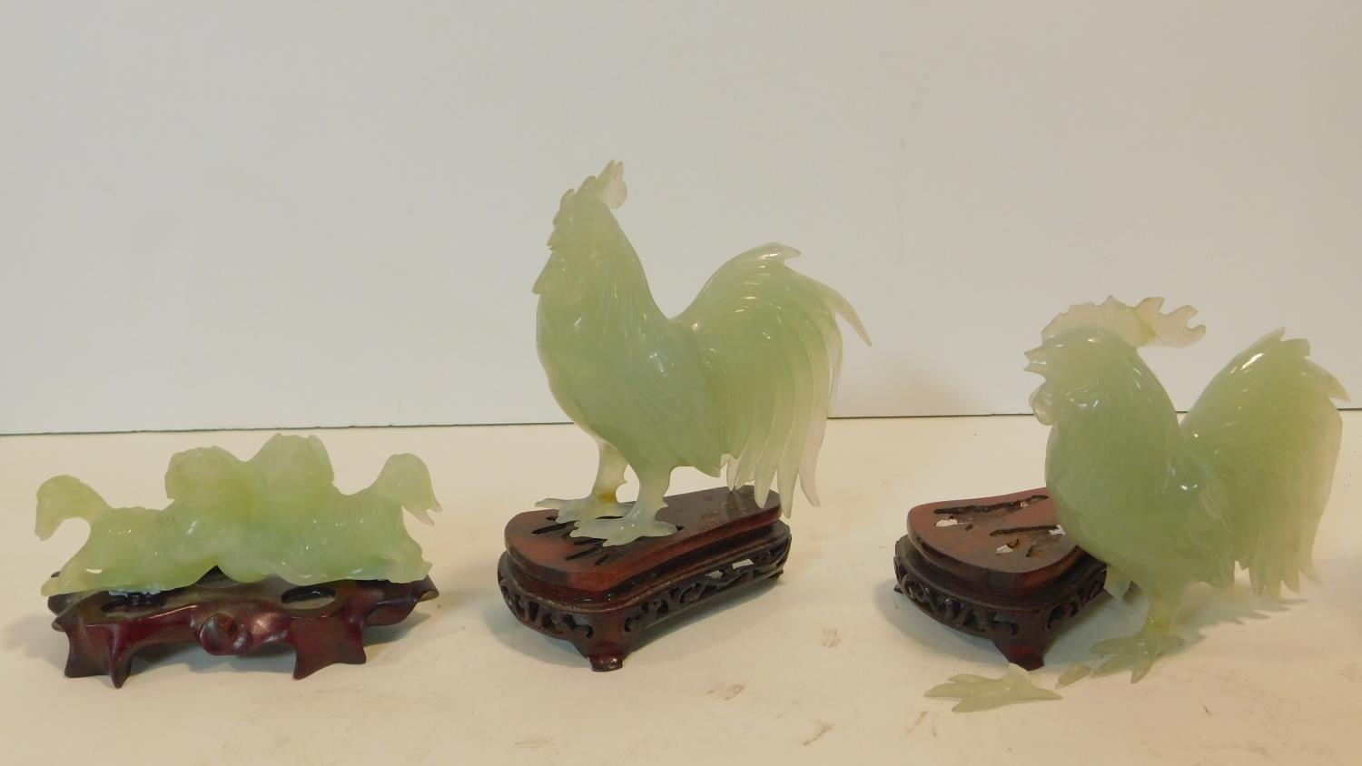 A Chinese carved jade figure of a pair of dogs on carved and pierced hardwood base and two similar