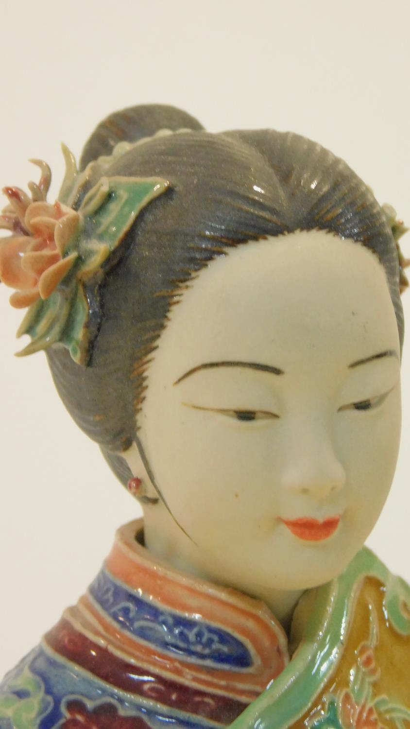 A Japanese ceramic figure of a lady sitting on a garden seat in polychrome hand painted decoration - Image 3 of 8