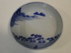 A Meji period blue and white ceramic Japanese bowl with hand painted village scene with mountains in