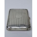 An leather lined Edwardian silver cigarette case with engine turned linear decoration, circular